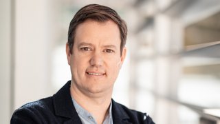 News Porträt eines Mannes mit verschränkten Armen in einem modernen Büro