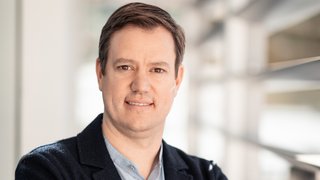 News Porträt eines Mannes mit verschränkten Armen in einem modernen Büro