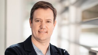 News Porträt eines Mannes mit verschränkten Armen in einem modernen Büro