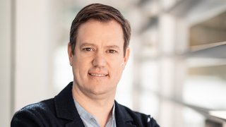 News Porträt eines Mannes mit verschränkten Armen in einem modernen Büro