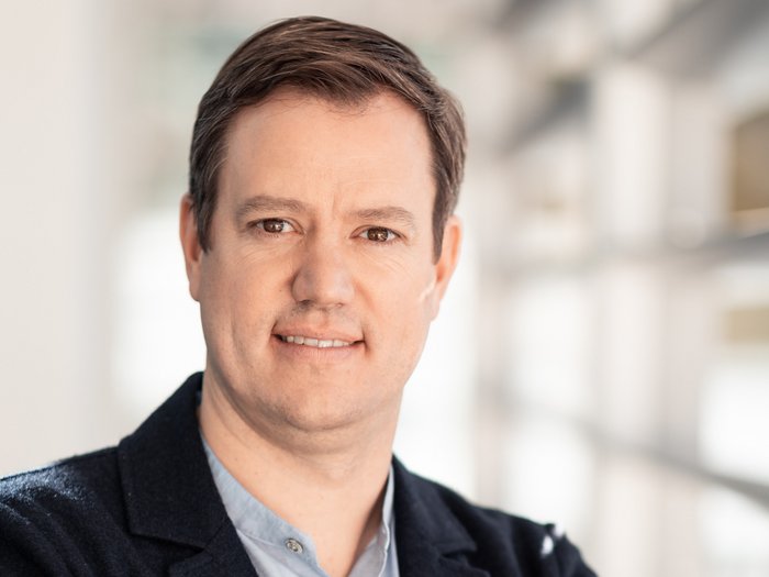 Die Chancen auf die Wohnbauförderung steigern Porträt eines Mannes mit verschränkten Armen in einem modernen Büro