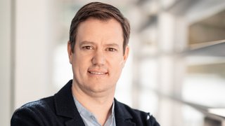 News Porträt eines Mannes mit verschränkten Armen in einem modernen Büro