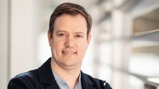 News Porträt eines Mannes mit verschränkten Armen in einem modernen Büro