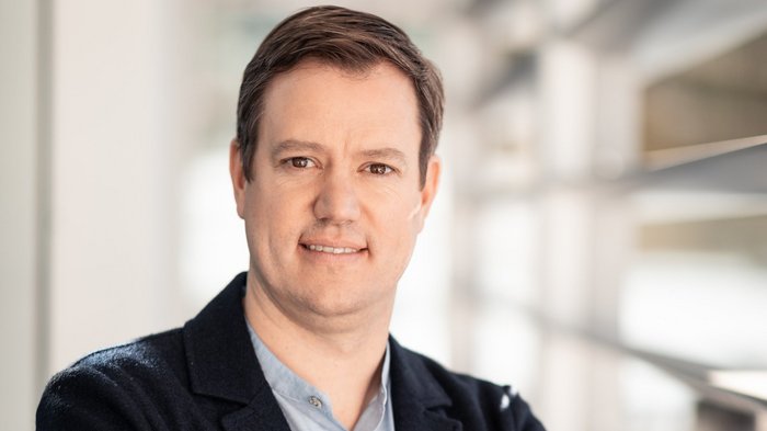 Corona-Impfung: endlich Ausweg in Sicht Porträt eines Mannes mit verschränkten Armen in einem modernen Büro