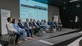 Anlaufstelle für Künstliche Intelligenz vorgestellt Podiumsdiskussion mit mehreren Personen auf der Bühne und Finanzierungsinformationen im Hintergrund