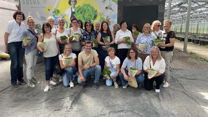 Spunti innovativi per le artigiane dell'Alta Val Pusteria Gruppo di persone in una serra con teste di lattuga fresca in mano