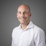 Das lvh-Team Porträt eines lächelnden Mannes mit weißem Hemd vor grauem Hintergrund