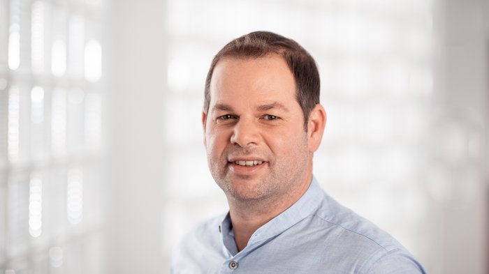 Das Recht auf Reparatur Porträt eines Mannes mit blauem Hemd vor hellem unscharfem Hintergrund