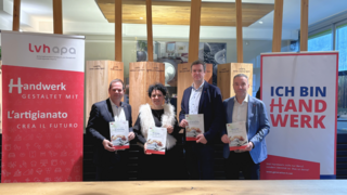 News Vier Personen halten Broschüren vor zwei Werbebannern mit Handwerksbotschaften