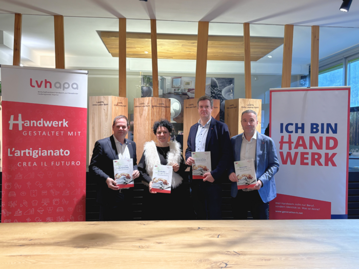 „Praxis vor Paragrafen“ – lvh fordert Bürokratie-Check zur Entlastung der Südtiroler Handwerksbetriebe Vier Personen halten Broschüren vor zwei Werbebannern mit Handwerksbotschaften