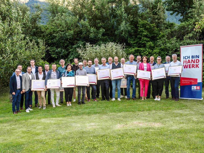 Consegna della spilla d’oro di lvh.apa Foto di gruppo di persone con certificati davanti a un banner Ich bin Handwerk all'aperto
