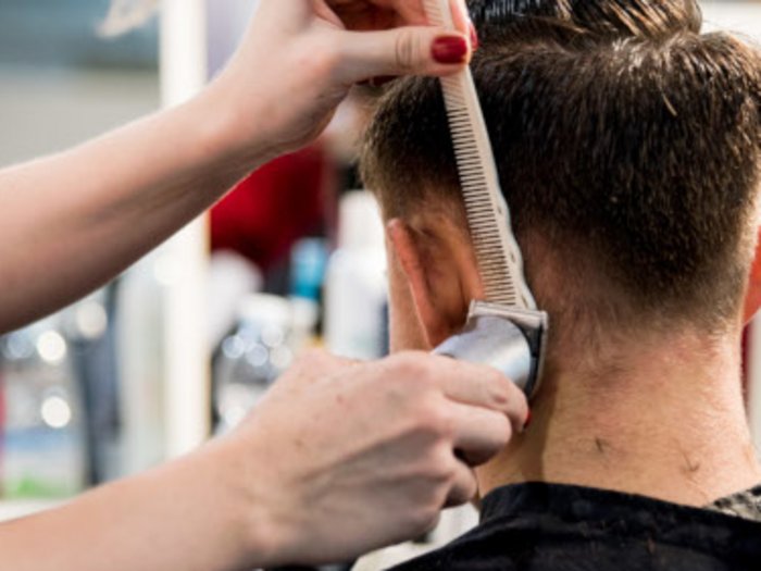 Körperpflegeberufe: „Drei Monate Stillstand sind schlichtweg inakzeptabel!“ Friseur schneidet Männern die Haare mit Haarschneidemaschine und Kamm