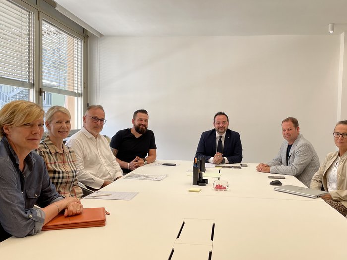 Discussione con l'Assessore provinciale Galateo sul tema della macellazione a domicilio Sette persone riunite intorno a un tavolo bianco in una sala riunioni luminosa