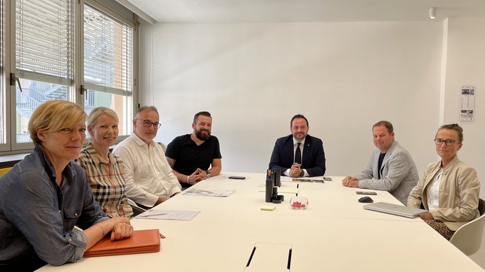 Aussprache mit Landesrat Galateo zum Thema Hausschlachtungen Sieben Personen bei einer Besprechung an einem weißen Konferenztisch in hellem Raum