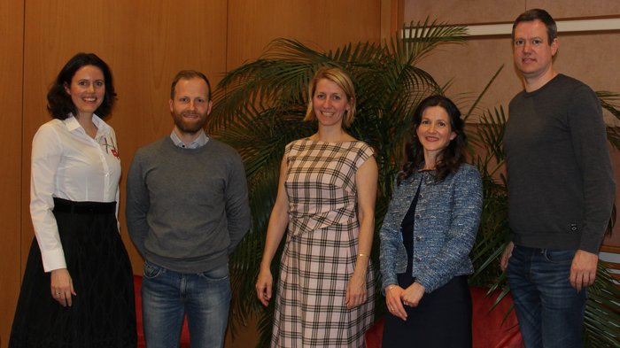 Assemblea annuale dei sarti su misura di lvh.apa Cinque persone in piedi davanti a piante e poltrone rosse in una stanza interna