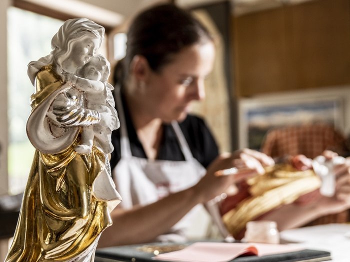 Più del “Made in Alto Adige”: l’Europa protegge l’artigianato Donna che restaura una statua religiosa dorata in un laboratorio