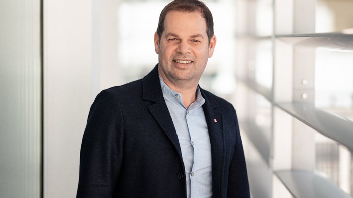 Wichtiger Schritt für Berufsorientierung Mann in Jacke und Hemd steht in modernem Gebäude am Fenster