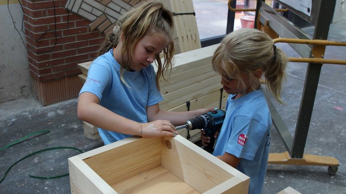 Kids-Academy 2024: Eine lehrreiche Erfahrung im Vinschgau Zwei Mädchen arbeiten gemeinsam an einem Holzprojekt mit einer Bohrmaschine