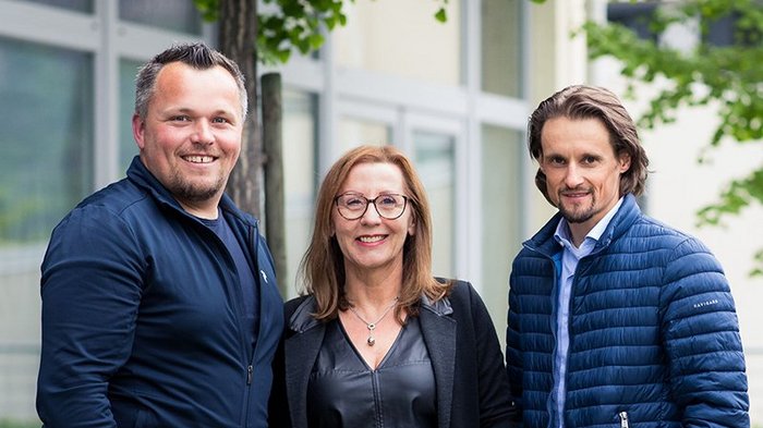 Medien, Design & IT: Die Qualität bildet den entscheidenden Unterschied Drei lächelnde Personen stehen vor einem Gebäude im Freien