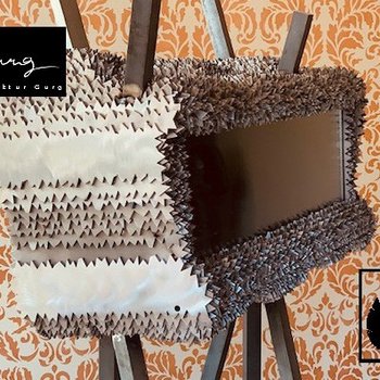 Manufaktur Gurg Scultura di parti di carta piegate davanti a uno sfondo decorato