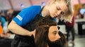 EuroSkills 2023: adesso bisogna concentrarsi! Parrucchiera che acconcia con concentrazione una testa di manichino maschile con capelli lunghi e barba