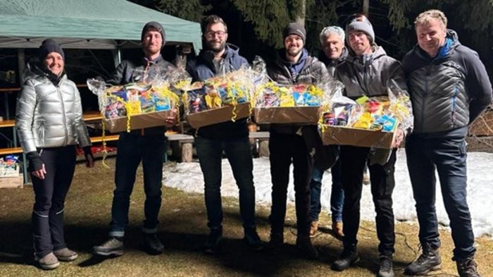 Lattlschießen der Handwerker/innen erfreut sich größter Beliebtheit Gruppe von sieben Personen mit Geschenkpaketen im Freien bei Nacht