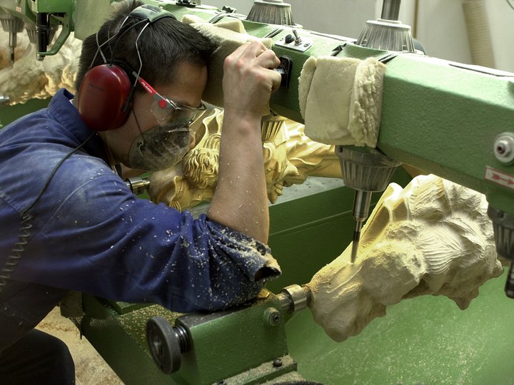 Maschinenschnitzer Handwerker schnitzt Holzfigur mit Maschine in Werkstatt