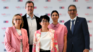 Kernthemen 2024 Fünf Personen formell und in pinkfarbenen Outfits vor Lvhb-Hintergrund