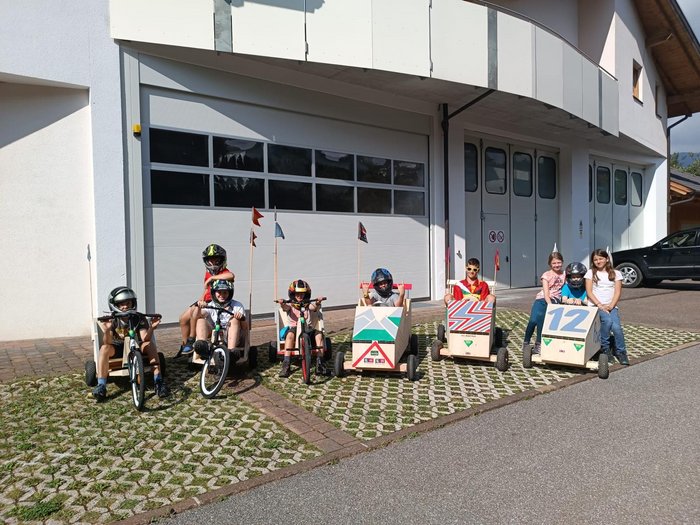 Gara di Soapbox a San Felice: l'artigianato corre veloce Bambini con soapbox fatti a mano davanti a un garage in una giornata di sole