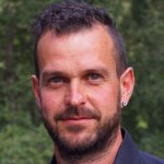 Unterpustertal/Gadertal Porträt eines Mannes mit kurzem Haar und Bart vor grünem Hintergrund