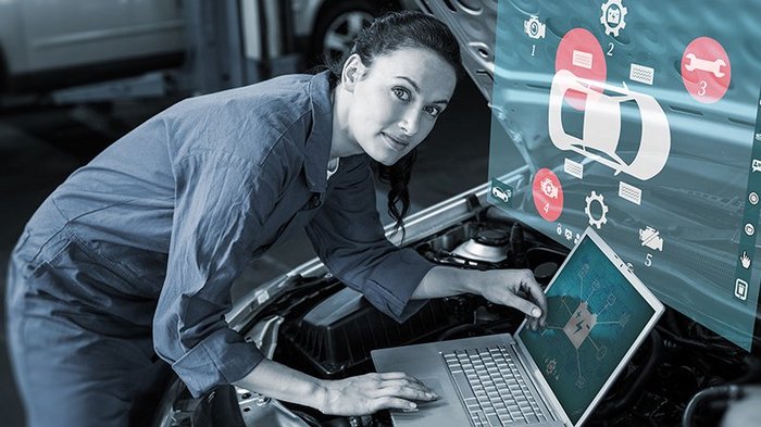 Aus der Krise lernen und sich weiterentwickeln Mechanikerin überprüft digitale Fahrzeugdiagnose mit Laptop an Auto