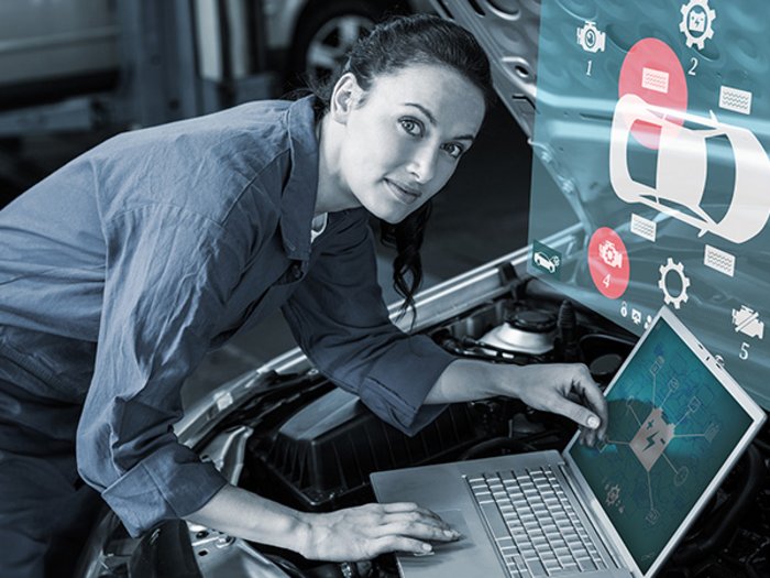 Aus der Krise lernen und sich weiterentwickeln Mechanikerin überprüft digitale Fahrzeugdiagnose mit Laptop an Auto