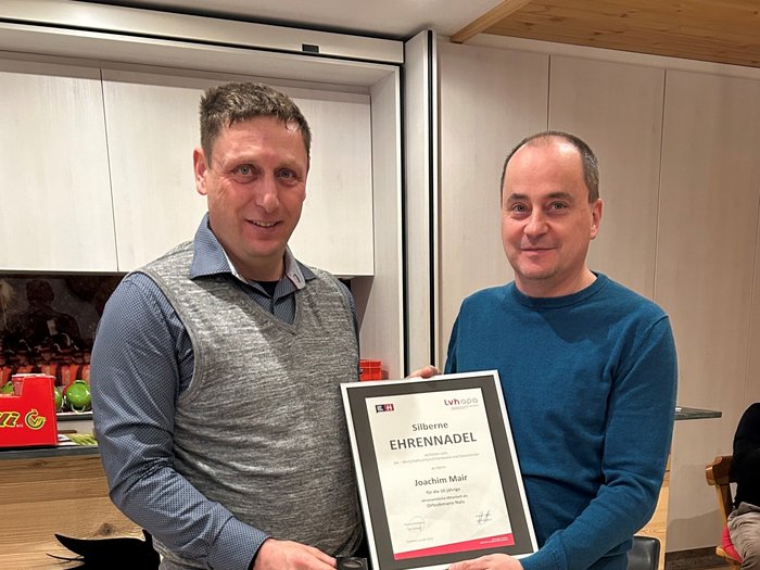 Mitreden, um mitzuentscheiden Zwei Männer halten eine gerahmte silberne Ehrennadel Auszeichnung.