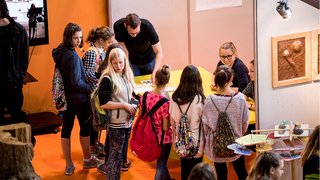 News Gruppe von Jugendlichen an einem Messestand mit Ausstellern im Gespräch