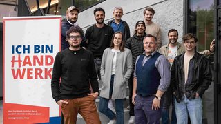 News Gruppe von zehn Personen vor einem Schild mit Ich bin Handwerk