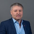 Elektrotechniker Porträt eines Mannes mittleren Alters mit kurzem grauem Haar und blauem Anzug vor grauem Hintergrund