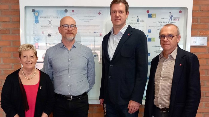 Importante incontro tra la dirigenza lvh.apa e la direzione della scuola professionale italiana Quattro persone in piedi davanti a una parete con premi e certificati