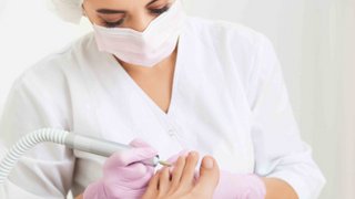 News Frau in medizinischer Schutzkleidung bei Fußbehandlung