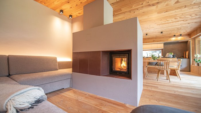 Tag des Kachelofens Modernes Wohnzimmer mit Kamin, grauem Sofa und Holzdecke