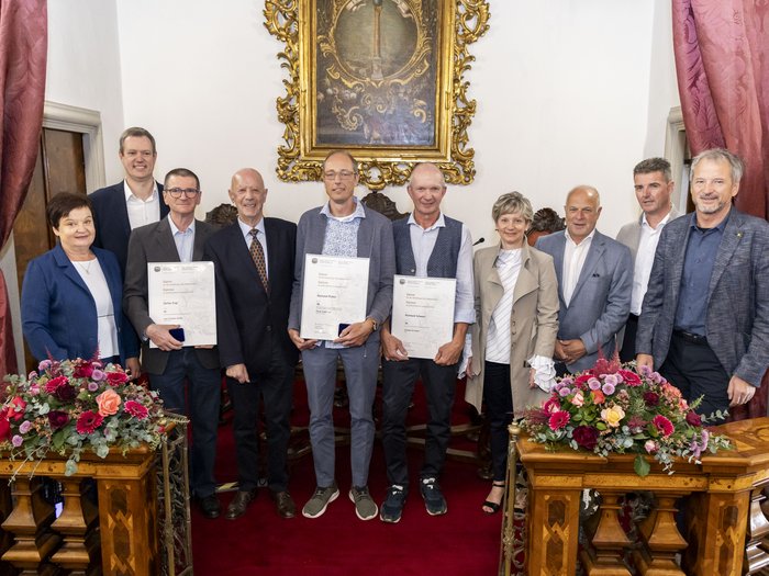 Collaboratori premiati Gruppo di persone in ambiente formale con fiori e certificati in mano