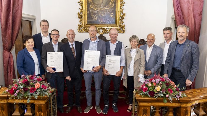 Collaboratori premiati Gruppo di persone in ambiente formale con fiori e certificati in mano