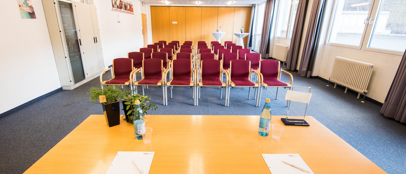 Affitto aule seminari Sala conferenze vuota con file di sedie, tavolo con blocchi per appunti e bottiglie d'acqua