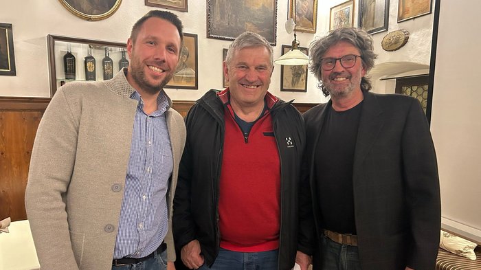 Tracciare la rotta per il futuro e rendere omaggio a un artigiano meritevole Tre uomini sorridenti in piedi in una stanza con quadri alle pareti