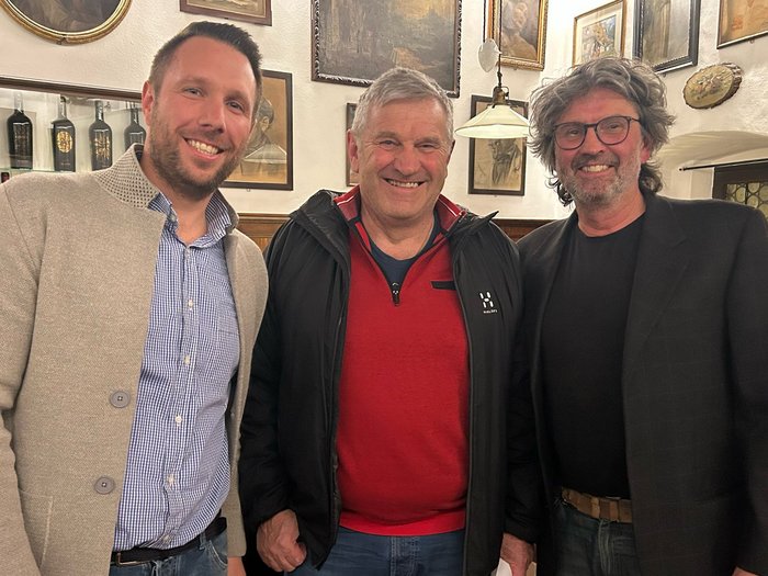 Tracciare la rotta per il futuro e rendere omaggio a un artigiano meritevole Tre uomini sorridenti in piedi in una stanza con quadri alle pareti