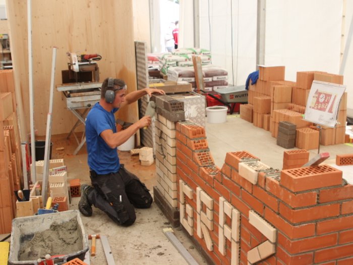 Costruttori e Muratori: uno sguardo al futuro Uomo che posa mattoni per un muro di mattoni in un cantiere