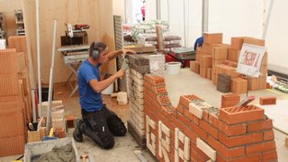 News Mann setzt Mauersteine für eine Ziegelmauer auf einer Baustelle