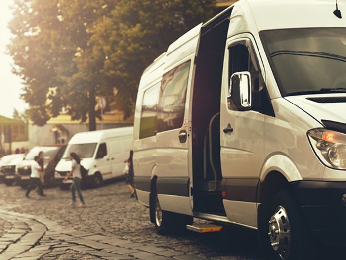 Neue Perspektiven für Südtirols Mietwagenunternehmen Weiße Transporter geparkt auf gepflasterter Straße bei Sonnenuntergang