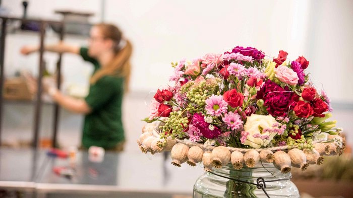 Muttertag: Geschenke für Superheldinnen Bunter Blumenstrauß in einer Vase mit unscharfer Person im Hintergrund