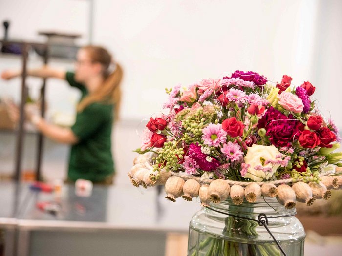 Muttertag: Geschenke für Superheldinnen Bunter Blumenstrauß in einer Vase mit unscharfer Person im Hintergrund