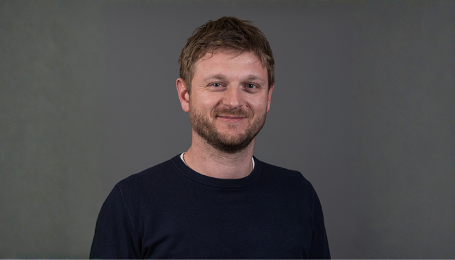 Home Porträt eines lächelnden Mannes mit Bart vor grauem Hintergrund